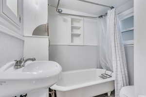 Full bathroom featuring shower / bath combo with shower curtain, sink, and toilet