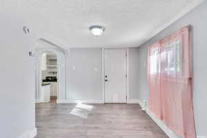 Foyer entrance with a textured ceiling and light hardwood / wood-style floors