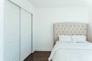 Guest bedroom with a closet and dark hardwood / wood-style flooring