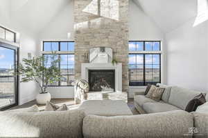 Living room featuring high vaulted ceiling, wood-type flooring, and a stone fireplace