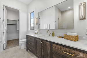 Bathroom featuring toilet, vanity, and walk in shower