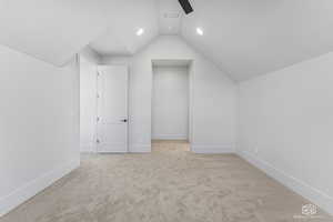 Additional living space featuring light colored carpet and lofted ceiling