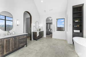 Bathroom with a bath, high vaulted ceiling, and vanity