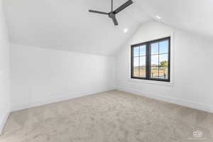 Additional living space with ceiling fan, light carpet, and vaulted ceiling