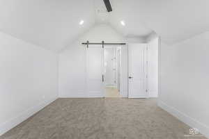 Bonus room with vaulted ceiling and light colored carpet