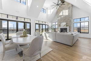 Dining space with a towering ceiling, light wood-type flooring, and a stone fireplace