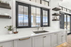 Kitchen featuring light stone counters, a healthy amount of sunlight, and sink