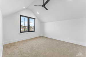 Bonus room with ceiling fan, vaulted ceiling, and light carpet