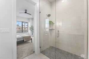 Bathroom featuring ceiling fan and a shower with door