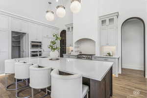 Kitchen featuring sink, decorative light fixtures, a kitchen island with sink, and decorative backsplash