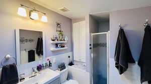 Bathroom with decorative backsplash, a shower with door, vanity, and toilet