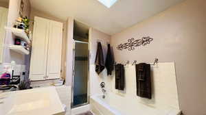 Bathroom with shower with separate bathtub, lofted ceiling, and sink