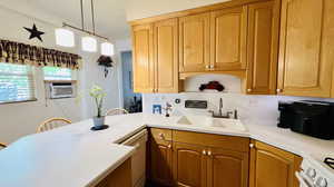 Kitchen featuring cooling unit, kitchen peninsula, sink, white appliances, and decorative light fixtures