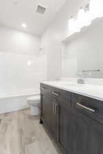 Full bathroom with  shower combination, vanity, hardwood / wood-style flooring, and toilet