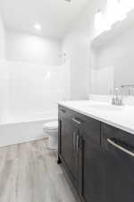 Full bathroom featuring vanity, toilet, shower / washtub combination, and hardwood / wood-style floors