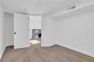 Unfurnished bedroom featuring a closet, a tiled fireplace, and carpet