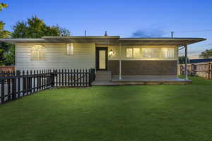 View of front of home featuring a yard Digitally enhanced yard and sky