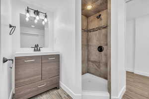 Bathroom with a tile shower, vanity, and hardwood / wood-style flooring