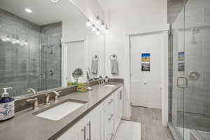 Bathroom featuring a shower with shower door and vanity