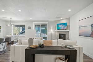 Living room with a textured ceiling, a tiled fireplace, and hardwood / wood-style flooring