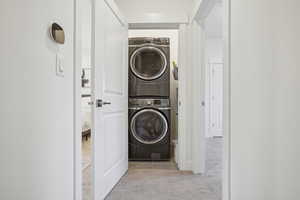 Washroom with light carpet and stacked washing maching and dryer