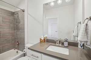 Full bathroom with tiled shower / bath, vanity, and toilet