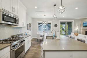 Kitchen with pendant lighting, stainless steel appliances, a center island with sink, and sink