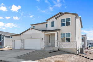 View of front of home featuring a garage and central AC unit