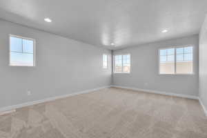 Empty room featuring carpet and a textured ceiling