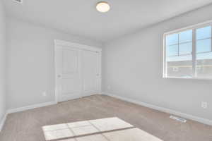 Unfurnished bedroom featuring a closet and light carpet