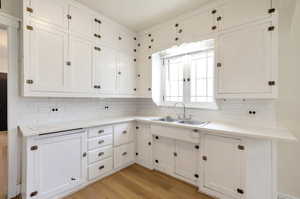 Kitchen featuring white cabinets, tasteful backsplash, light wood-type flooring, and sink