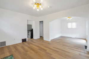 Unfurnished room with an inviting chandelier and light hardwood / wood-style flooring