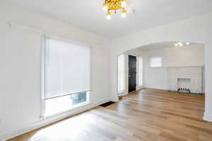 Unfurnished living room featuring light hardwood / wood-style floors, a fireplace, and a notable chandelier