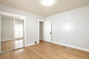 Unfurnished bedroom with light hardwood / wood-style floors and a closet