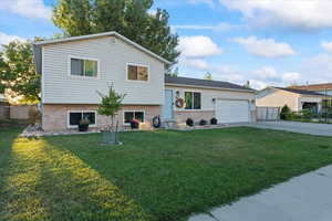 Tri-level home featuring a garage and a front lawn