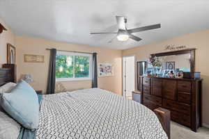 Carpeted bedroom featuring a textured ceiling and ceiling fan