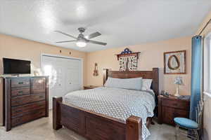 Bedroom featuring a textured ceiling, light carpet, ceiling fan, and a closet