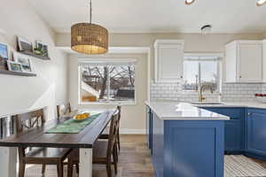 Kitchen featuring blue cabinets, decorative light fixtures, decorative backsplash, a center island, and a wealth of natural light