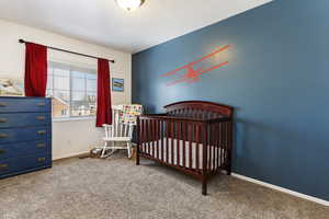 Carpeted bedroom with a crib and a textured ceiling