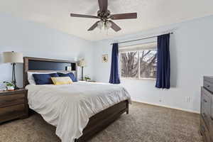 Bedroom featuring ceiling fan, carpet flooring, and a textured ceiling