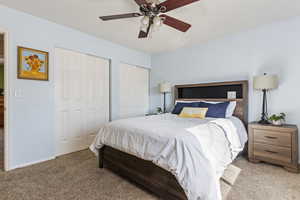 Bedroom featuring light carpet, two closets, and ceiling fan