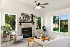 Living room featuring ceiling fan, a fireplace, and vaulted ceiling