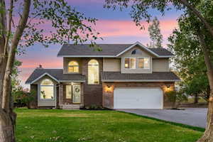 View of front of property featuring a luscious lawn and a 2-car garage