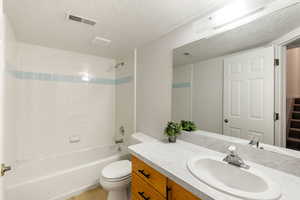 Full basement bathroom featuring a tiled shower/bath combo, vanity, and toilet