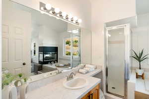 Primary bathroom featuring vanity, a multi sided fireplace, and a shower with shower door