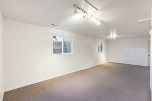 Storage/hobby room featuring a textured ceiling and rail lighting, adjacent to cold storage room under the front porch