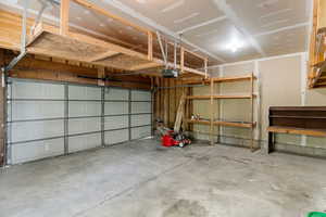 Garage featuring a garage door opener, shelving and a workbench