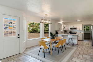 Dining area with a textured ceiling, a notable chandelier, sink, and plenty of natural light