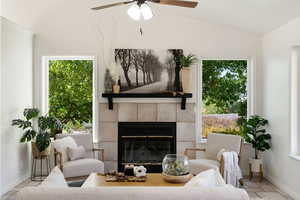 Living room with ceiling fan, a fireplace, plenty of natural light, and vaulted ceiling