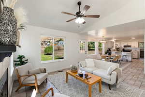 Tiled living room with ceiling fan with notable chandelier and vaulted ceiling